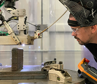 Man in safety goggles looking closely at metal making machine